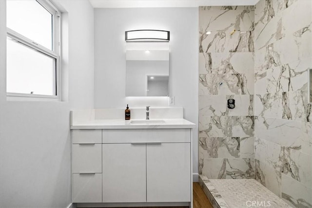 bathroom featuring a tile shower and vanity