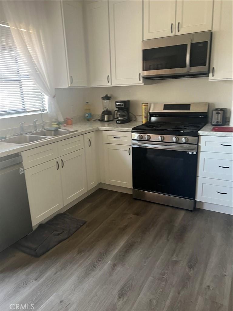 kitchen featuring light countertops, appliances with stainless steel finishes, a sink, and white cabinets