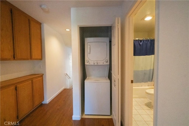 corridor with baseboards, light wood finished floors, recessed lighting, and stacked washer / drying machine