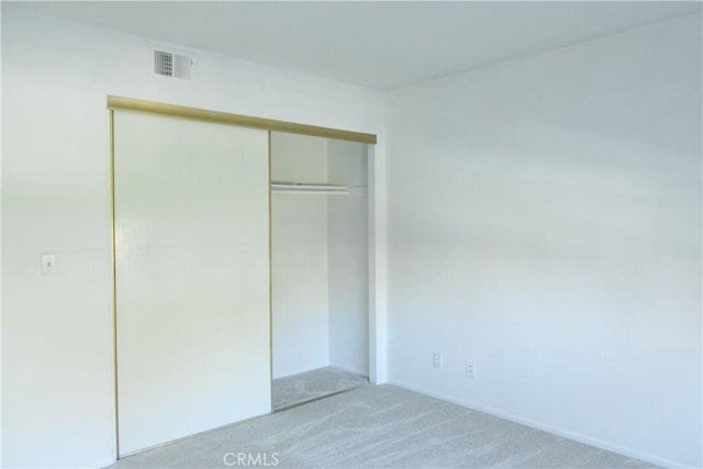 unfurnished bedroom featuring carpet floors, visible vents, and a closet