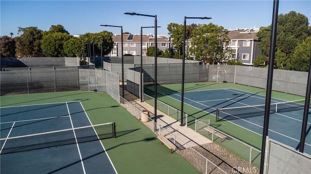 view of tennis court featuring community basketball court, a residential view, and fence