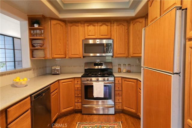 kitchen with backsplash, appliances with stainless steel finishes, light countertops, and dark wood finished floors