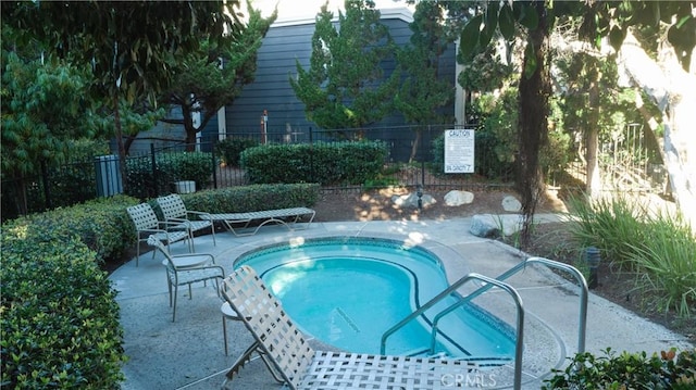 view of swimming pool featuring a patio area, fence, and a hot tub