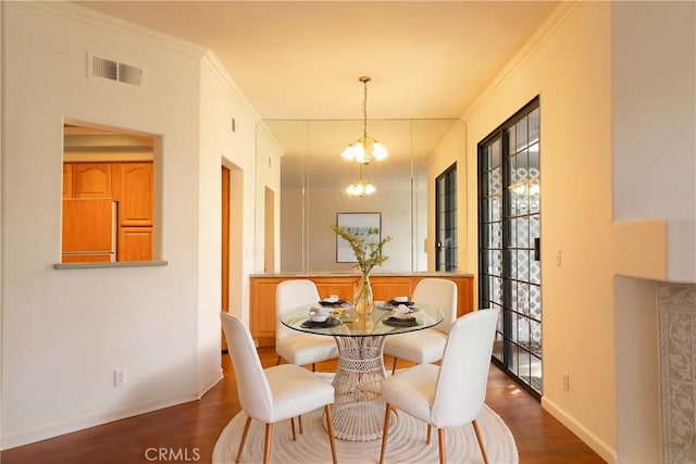 dining room with crown molding, wood finished floors, visible vents, and an inviting chandelier