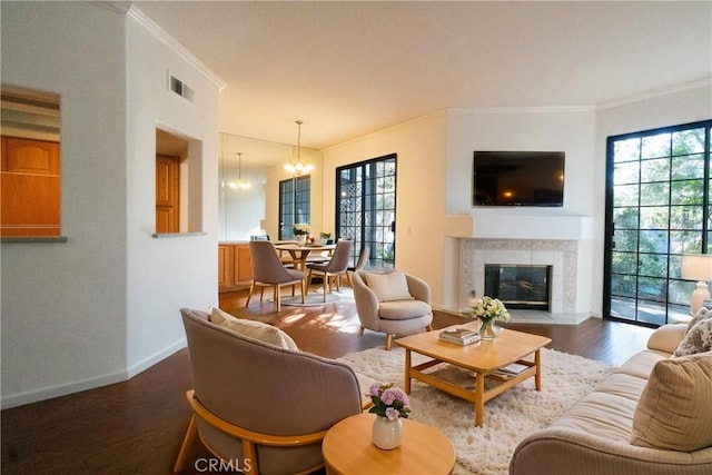 living area featuring a fireplace, wood finished floors, visible vents, baseboards, and an inviting chandelier