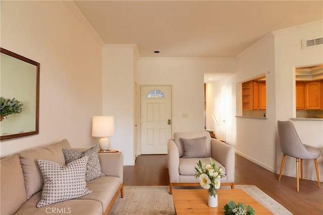 living area with ornamental molding, wood finished floors, visible vents, and baseboards