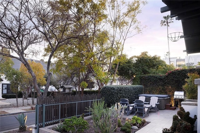 view of patio / terrace with a hot tub and fence