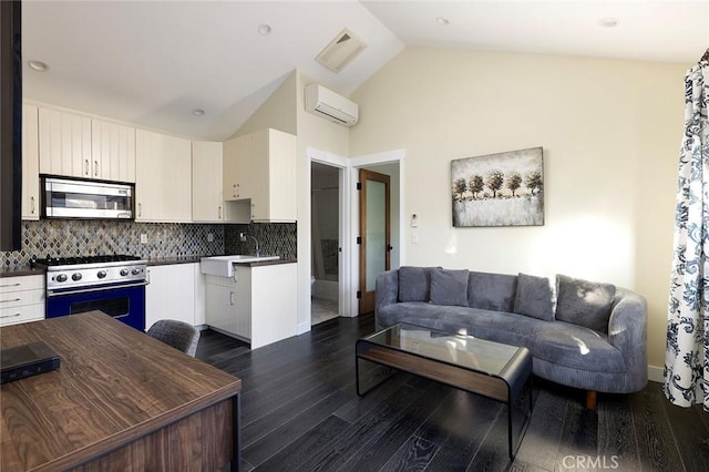 kitchen featuring a wall unit AC, a sink, stainless steel microwave, dark countertops, and range with gas cooktop