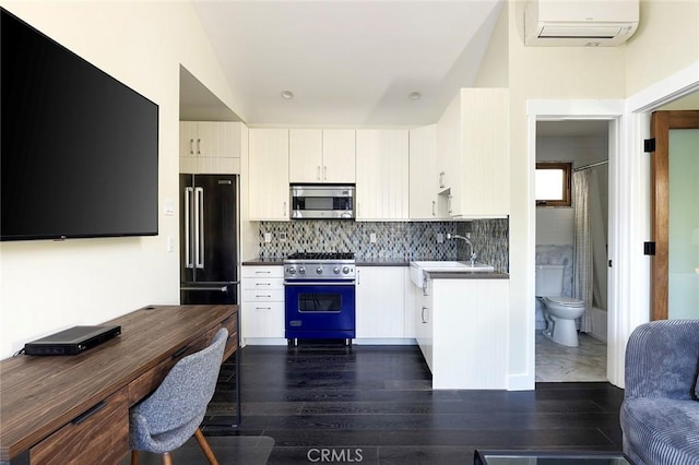 kitchen with dark wood finished floors, high quality appliances, a sink, backsplash, and a wall mounted AC