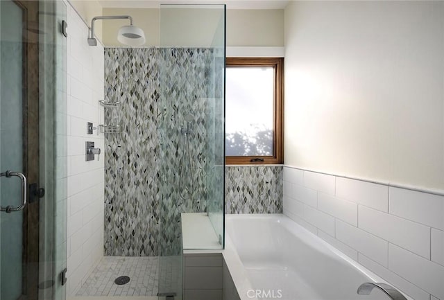 bathroom featuring a shower stall and a bath