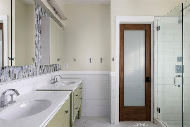 bathroom featuring tile walls, wainscoting, a sink, and a shower stall