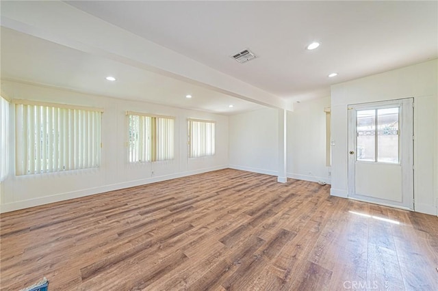 spare room featuring baseboards, visible vents, wood finished floors, beamed ceiling, and recessed lighting