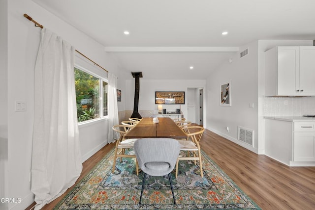 dining space with a wood stove, wood finished floors, visible vents, and recessed lighting