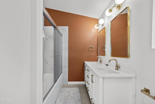 full bath featuring double vanity, bath / shower combo with glass door, tile patterned flooring, and a sink