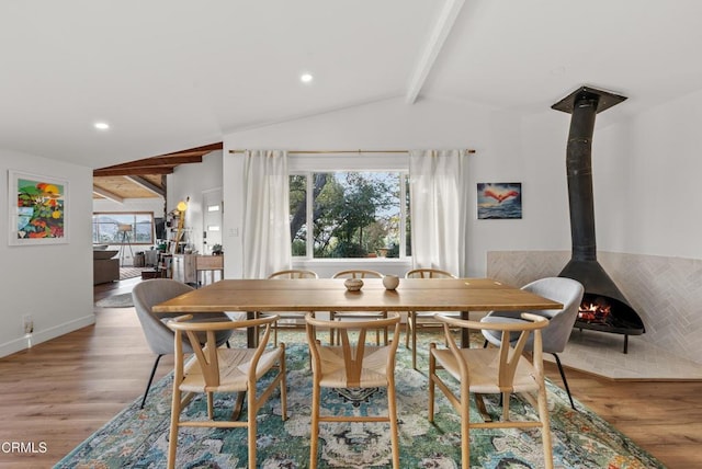 dining area featuring lofted ceiling with beams, a wood stove, wood finished floors, and recessed lighting