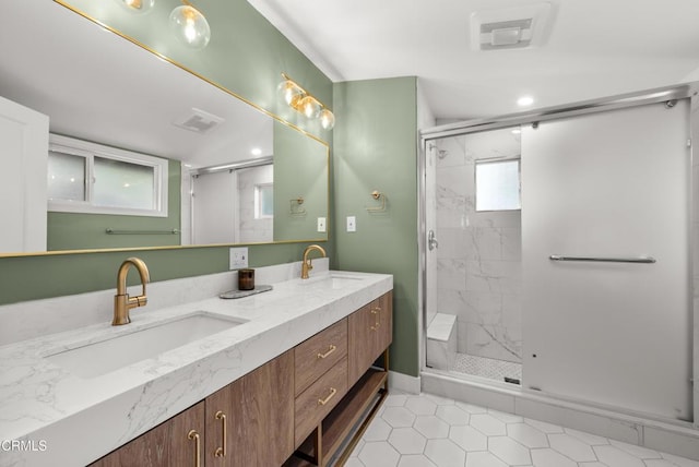 full bath featuring visible vents, a sink, and a marble finish shower