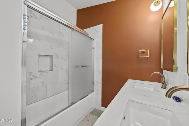 bathroom featuring double vanity, shower / bath combination with glass door, and a sink