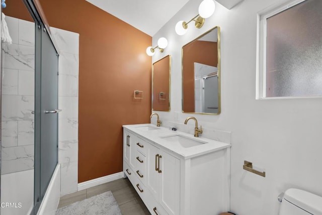 full bath with baseboards, a sink, toilet, and double vanity