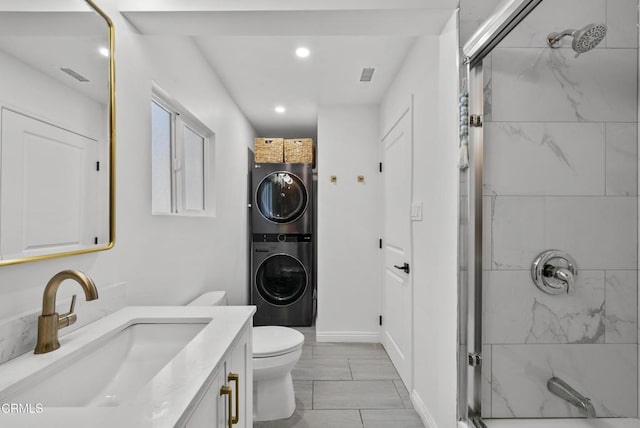 bathroom with stacked washer and dryer, visible vents, toilet, vanity, and a shower stall