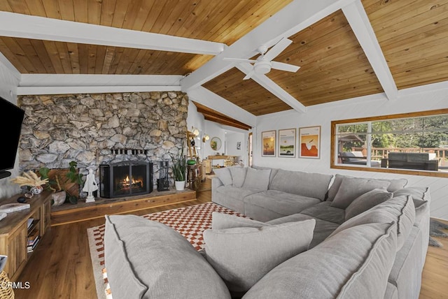 living area featuring ceiling fan, a fireplace, lofted ceiling with beams, and wood finished floors