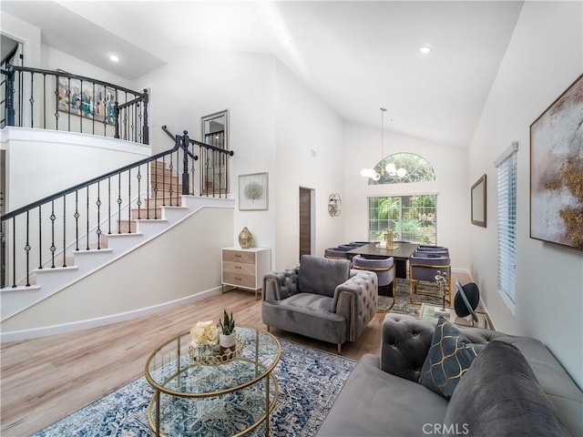 living room featuring a notable chandelier, recessed lighting, wood finished floors, high vaulted ceiling, and stairs