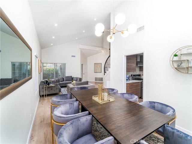 dining room with high vaulted ceiling, light wood-style flooring, a notable chandelier, visible vents, and stairway