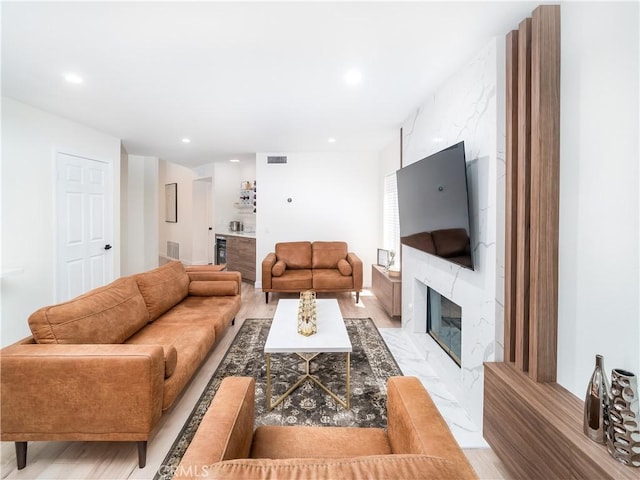 living area featuring a bar, a premium fireplace, visible vents, and recessed lighting