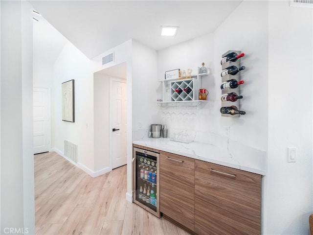 bar with a dry bar, light wood-type flooring, beverage cooler, and visible vents