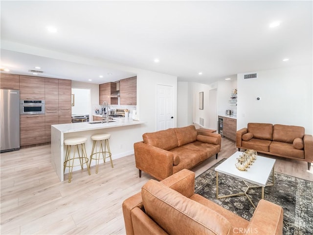 living room featuring recessed lighting, visible vents, and light wood finished floors