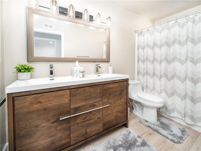 full bath featuring toilet, a shower with shower curtain, wood finished floors, vanity, and visible vents