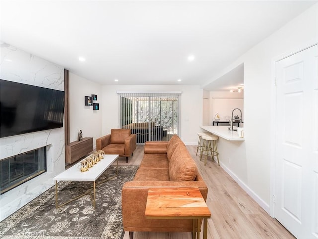 living area featuring light wood-type flooring, a high end fireplace, baseboards, and recessed lighting