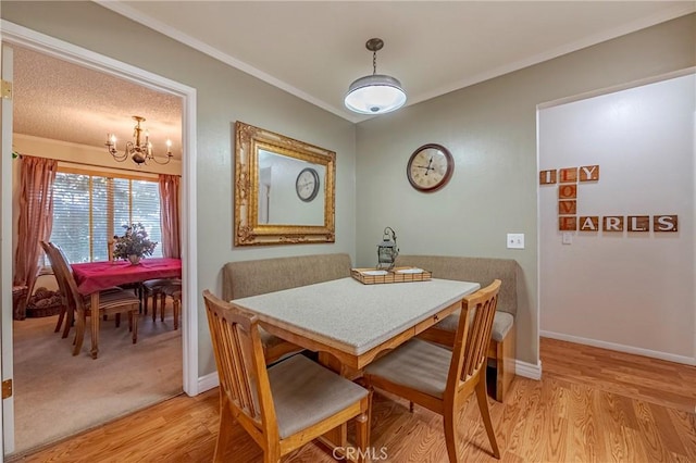 dining space featuring light wood-type flooring, crown molding, baseboards, and an inviting chandelier