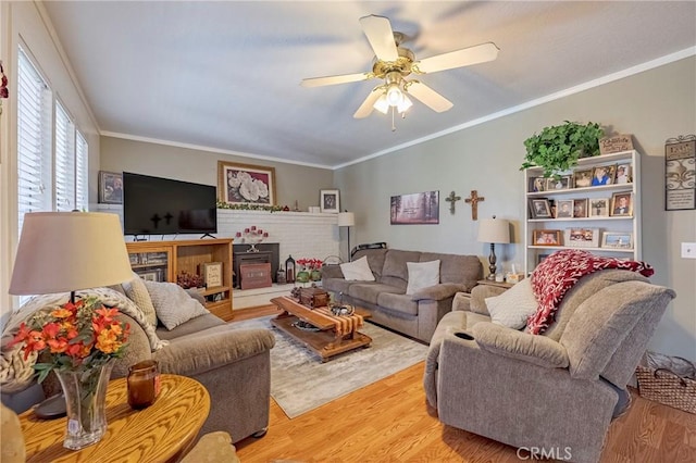 living room with crown molding, a ceiling fan, and light wood-style floors