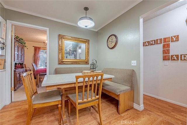 dining room featuring ornamental molding, breakfast area, light wood-style flooring, and baseboards