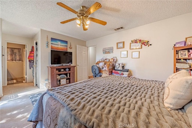 bedroom with carpet floors, visible vents, a textured ceiling, and a ceiling fan