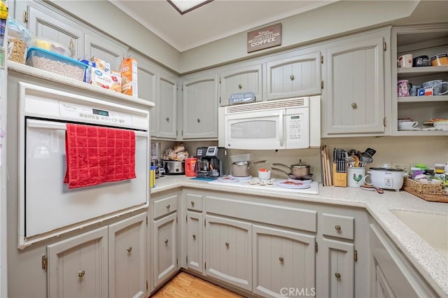 kitchen with white appliances, light countertops, a sink, and light wood finished floors