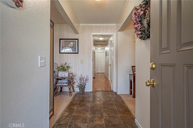 hall featuring a textured ceiling and baseboards