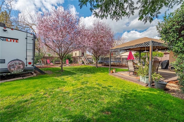 view of yard featuring a patio area, a fenced backyard, a trampoline, and a playground