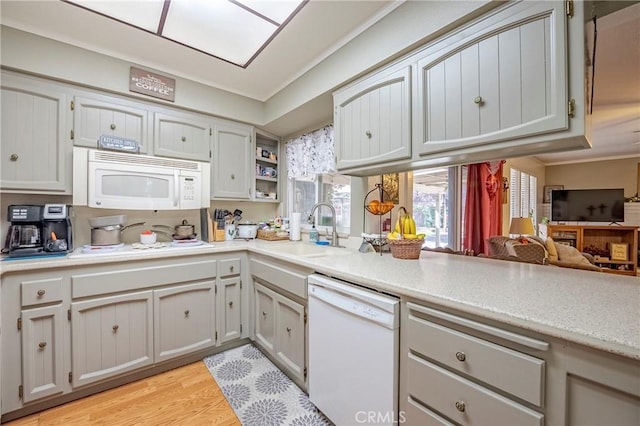 kitchen featuring open shelves, light countertops, light wood-style floors, a sink, and white appliances