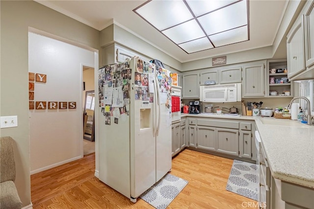 kitchen featuring light wood finished floors, open shelves, ornamental molding, a sink, and white appliances