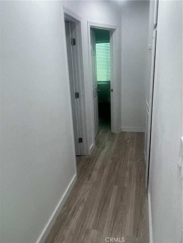 hallway featuring baseboards and wood finished floors