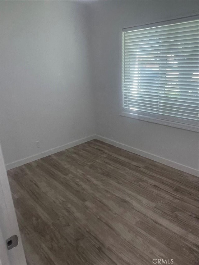 empty room featuring dark wood-style floors and baseboards