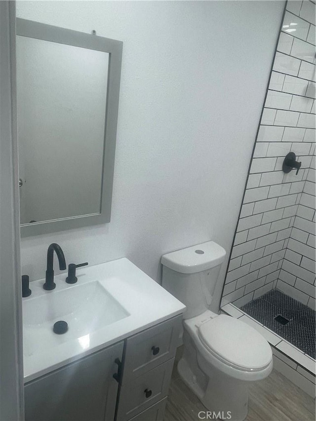 full bath with toilet, a shower stall, wood finished floors, and vanity