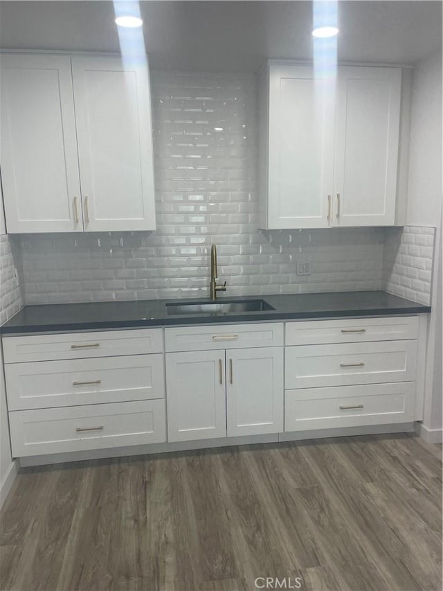 kitchen featuring dark countertops, white cabinets, dark wood-style flooring, and a sink