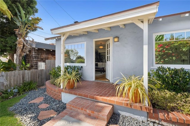 view of exterior entry featuring fence and stucco siding