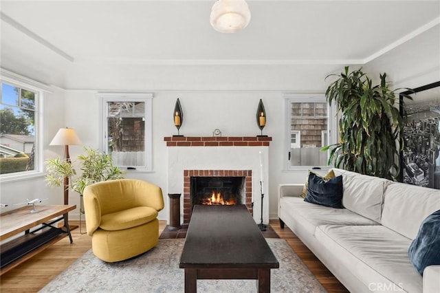 living room featuring a brick fireplace and wood finished floors