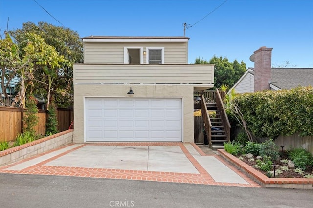 view of front of property featuring an attached garage, fence, stairs, driveway, and stucco siding