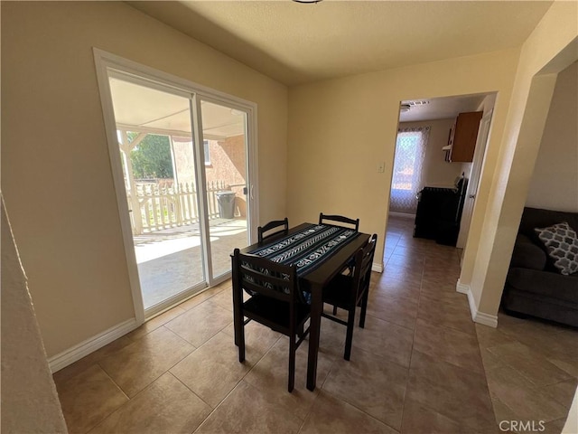 dining space featuring light tile patterned flooring and baseboards