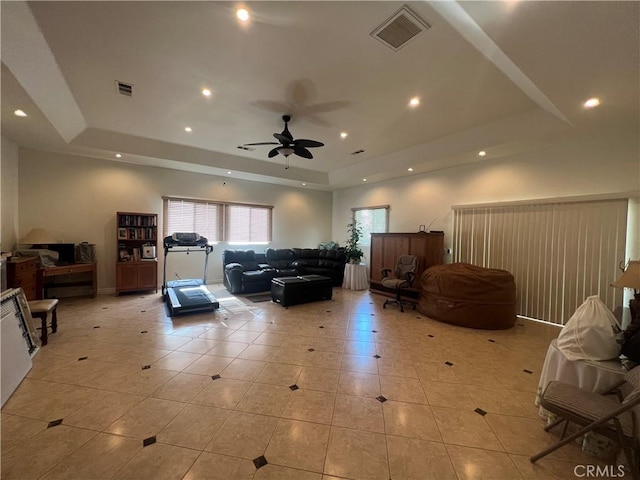 living area with light tile patterned floors, visible vents, a raised ceiling, and recessed lighting