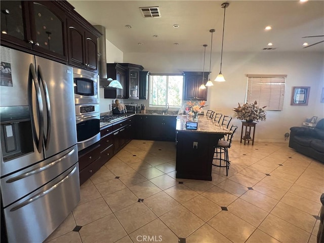 kitchen with light tile patterned floors, visible vents, glass insert cabinets, appliances with stainless steel finishes, and a kitchen bar